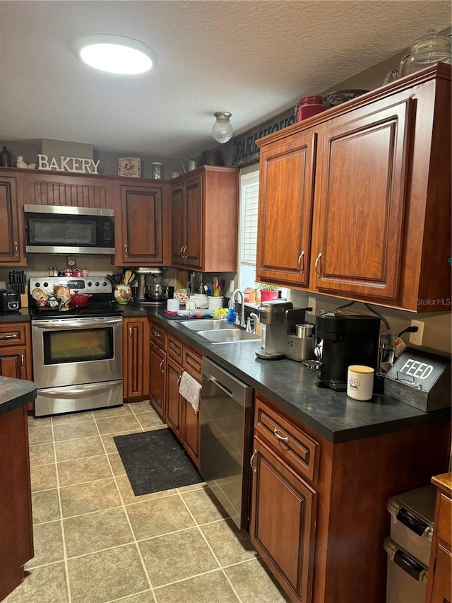 kitchen featuring sink, light tile patterned floors, a textured ceiling, and appliances with stainless steel finishes