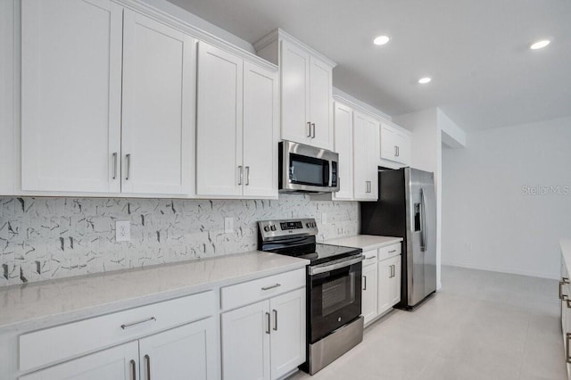 kitchen featuring stainless steel appliances, white cabinetry, backsplash, and light stone countertops