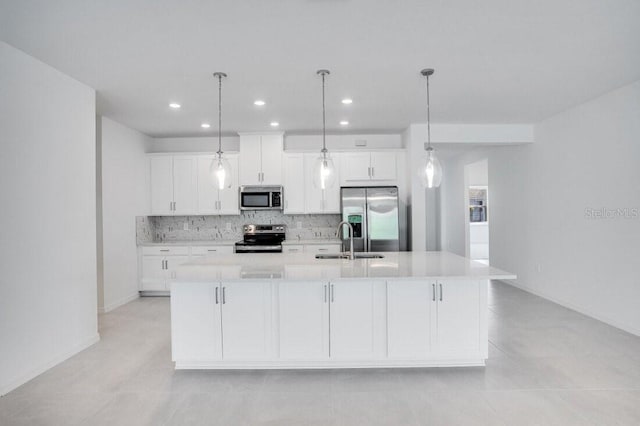 kitchen featuring stainless steel appliances, tasteful backsplash, a large island with sink, white cabinets, and sink