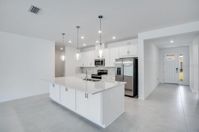 kitchen with decorative light fixtures, an island with sink, white cabinets, appliances with stainless steel finishes, and sink