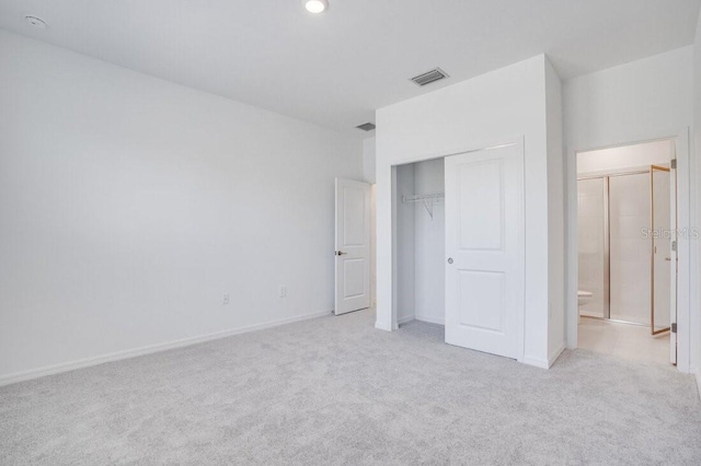 unfurnished bedroom with a closet and light carpet