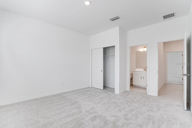 unfurnished bedroom with connected bathroom, a closet, and light carpet