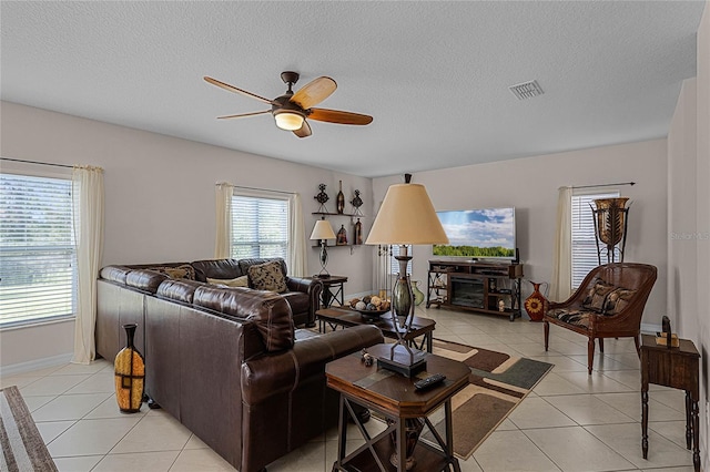 living room with ceiling fan, light tile patterned floors, and a textured ceiling