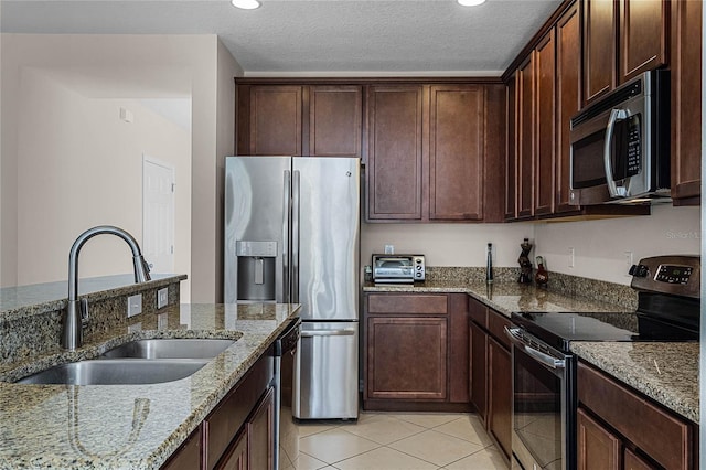 kitchen featuring light stone countertops, appliances with stainless steel finishes, a textured ceiling, and sink