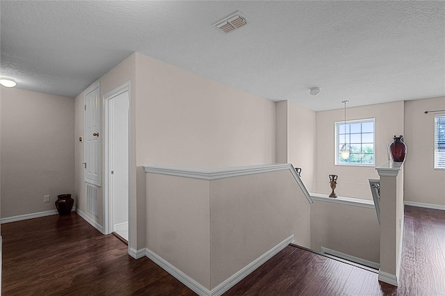 hall with dark wood-type flooring and a textured ceiling