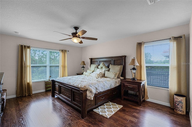 bedroom featuring a textured ceiling, dark hardwood / wood-style flooring, multiple windows, and ceiling fan