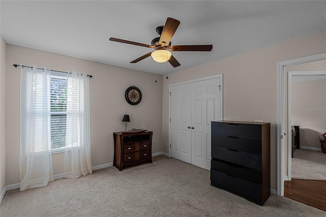 bedroom featuring ceiling fan, light carpet, and a textured ceiling