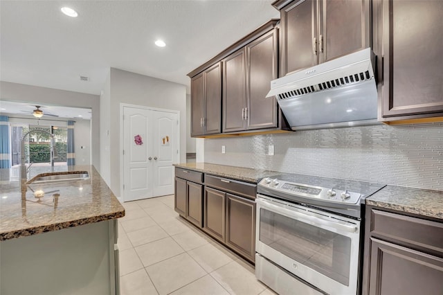 kitchen with stainless steel range with electric cooktop, ceiling fan, decorative backsplash, light stone counters, and sink