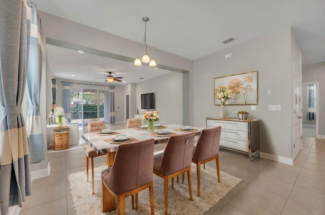 tiled dining area with ceiling fan with notable chandelier