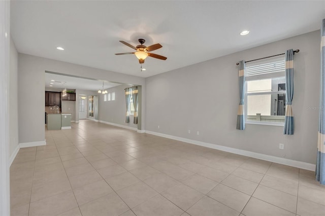 spare room with ceiling fan with notable chandelier and light tile patterned floors