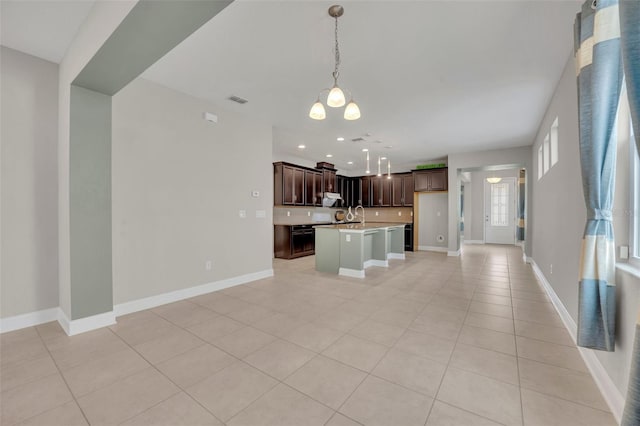 kitchen featuring an inviting chandelier, light tile patterned floors, an island with sink, decorative light fixtures, and dark brown cabinets