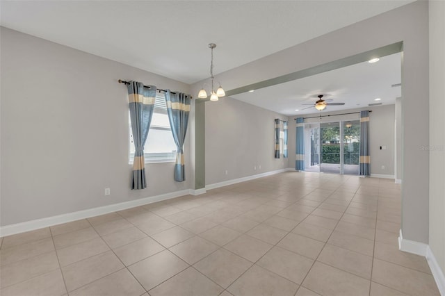 unfurnished room featuring light tile patterned floors and ceiling fan with notable chandelier