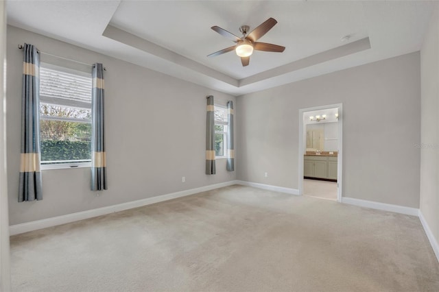 carpeted empty room featuring a raised ceiling and ceiling fan