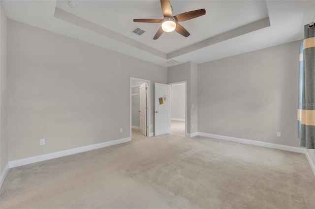 carpeted spare room featuring a raised ceiling and ceiling fan