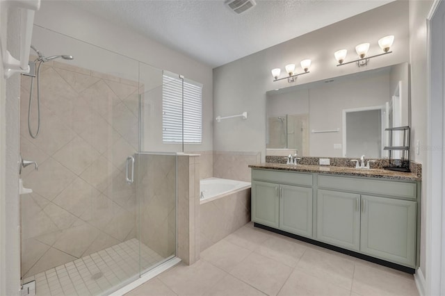 bathroom featuring a textured ceiling, independent shower and bath, tile patterned floors, and vanity