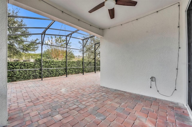 view of patio with ceiling fan and glass enclosure