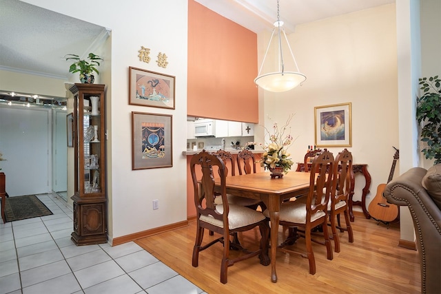 dining room featuring a textured ceiling, light wood-type flooring, and ornamental molding