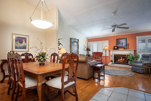 dining area with vaulted ceiling, light hardwood / wood-style flooring, ceiling fan, ornamental molding, and a textured ceiling