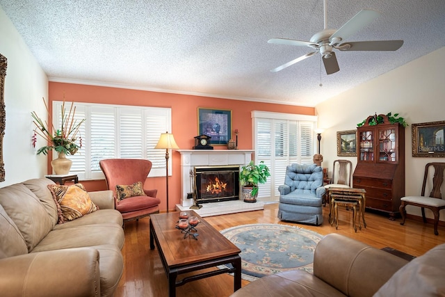 living room with a textured ceiling, hardwood / wood-style flooring, ceiling fan, and crown molding