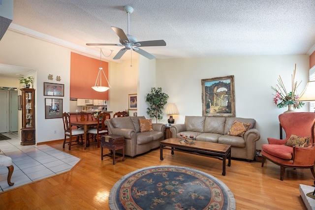 living room with wood-type flooring, a textured ceiling, vaulted ceiling, and ceiling fan