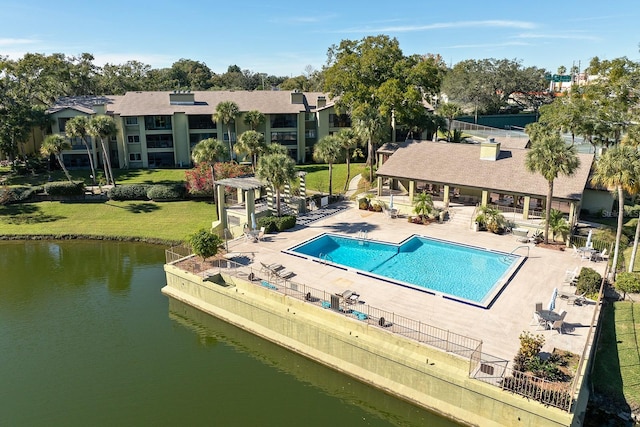 view of pool with a patio area, a yard, and a water view