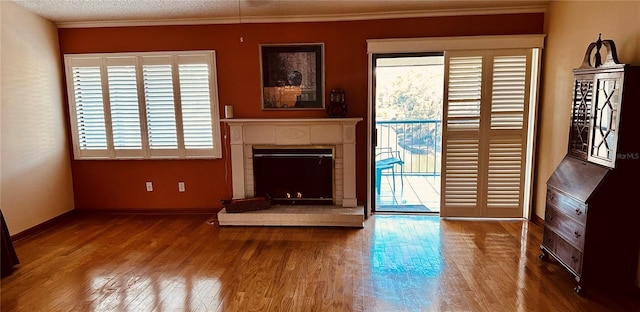 unfurnished living room with wood-type flooring, a textured ceiling, and ornamental molding