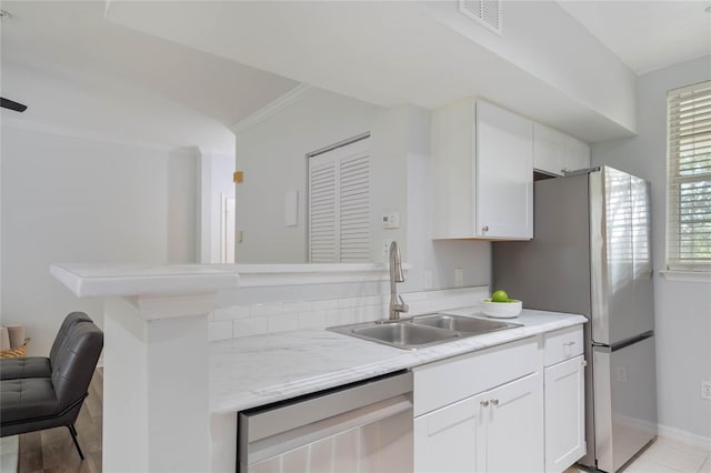 kitchen with kitchen peninsula, stainless steel appliances, crown molding, sink, and white cabinets