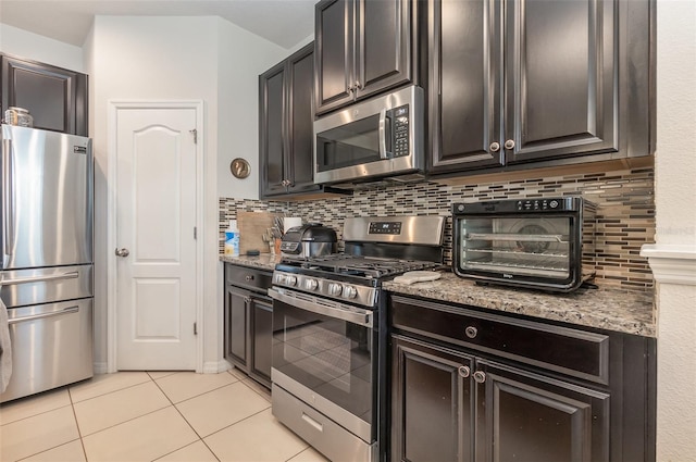 kitchen with light stone countertops, appliances with stainless steel finishes, tasteful backsplash, and light tile patterned flooring