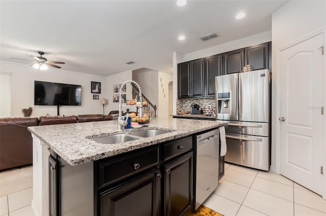 kitchen with a center island with sink, sink, ceiling fan, light tile patterned flooring, and stainless steel appliances