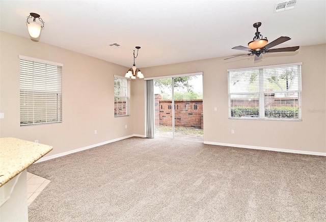 interior space with light colored carpet and ceiling fan with notable chandelier