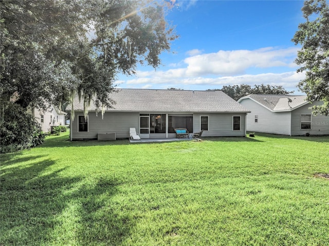 back of property with a yard, a shingled roof, and a sunroom