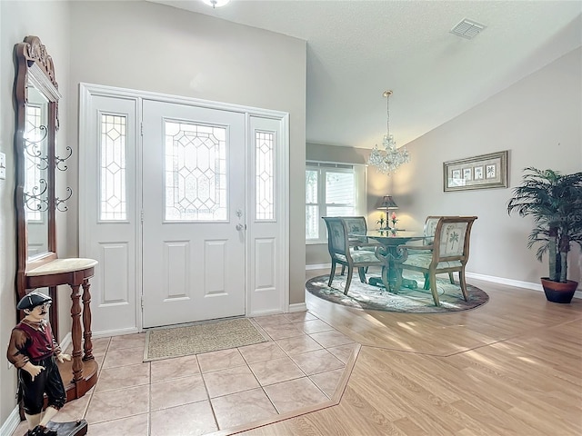 tiled foyer entrance with an inviting chandelier and lofted ceiling