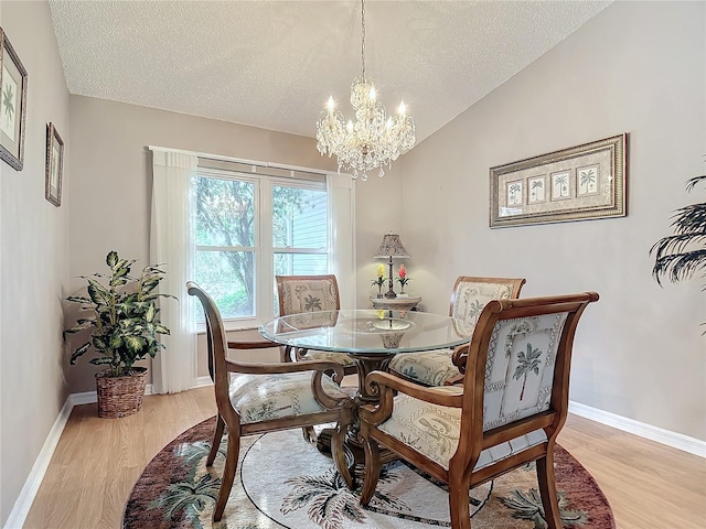 dining area with an inviting chandelier, vaulted ceiling, a textured ceiling, and light wood-type flooring