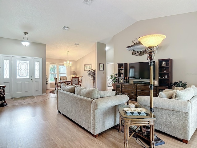 living room featuring vaulted ceiling, a notable chandelier, and light hardwood / wood-style floors