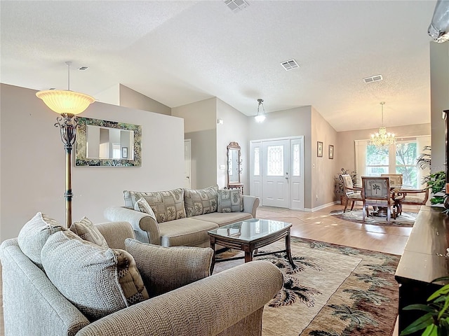 living room with vaulted ceiling, a textured ceiling, an inviting chandelier, and light hardwood / wood-style floors