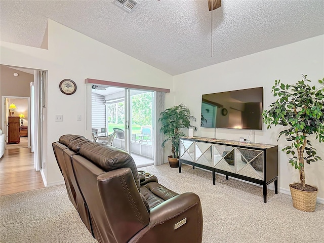 living room featuring vaulted ceiling, light carpet, ceiling fan, and a textured ceiling