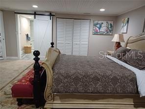 bedroom with a barn door and carpet floors