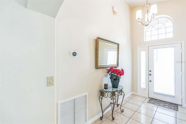 tiled entryway featuring plenty of natural light, a chandelier, and a high ceiling