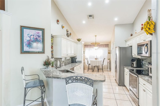 kitchen with backsplash, white cabinets, sink, kitchen peninsula, and stainless steel appliances