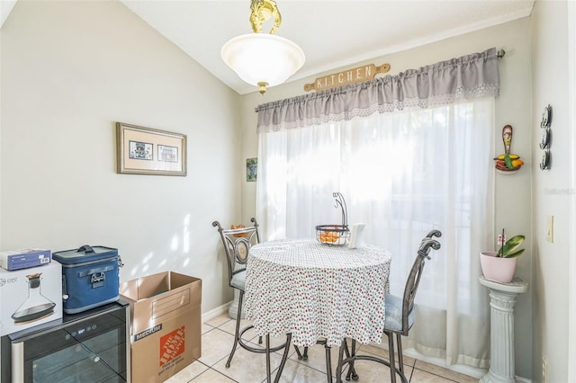 tiled dining space with beverage cooler and vaulted ceiling