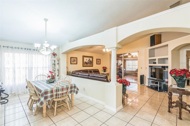 tiled dining area with a textured ceiling, ornate columns, built in shelves, and ceiling fan with notable chandelier