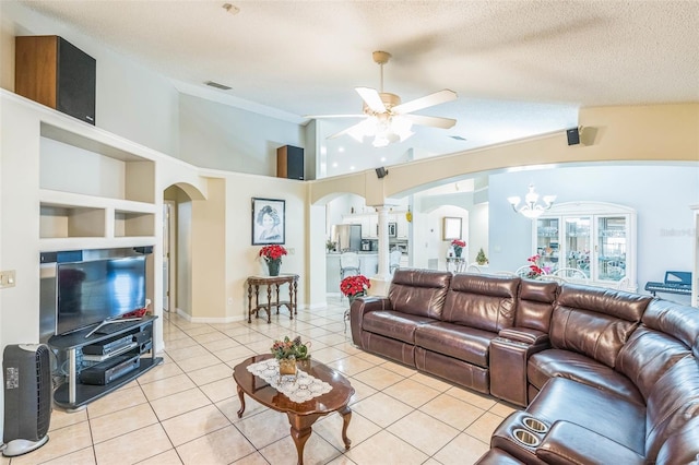 tiled living room with built in shelves, ceiling fan with notable chandelier, a textured ceiling, and high vaulted ceiling