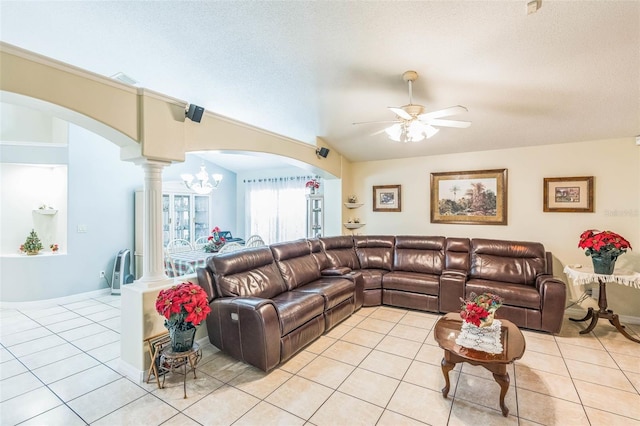 tiled living room featuring a textured ceiling, ceiling fan with notable chandelier, and ornate columns