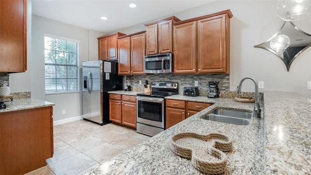 kitchen featuring sink, light stone countertops, stainless steel appliances, and tasteful backsplash