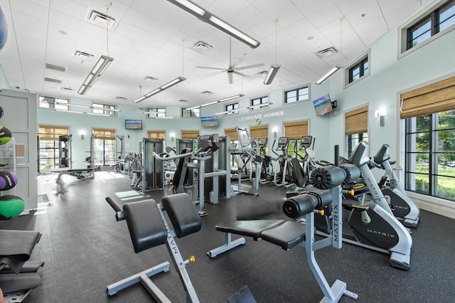 workout area with a towering ceiling, ceiling fan, and a paneled ceiling