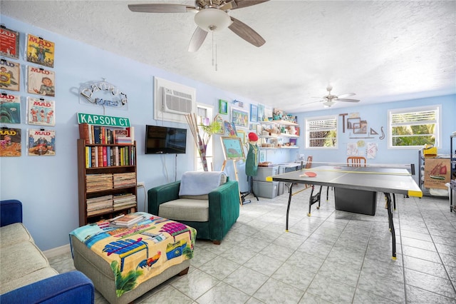 playroom featuring an AC wall unit, ceiling fan, light tile patterned floors, and a textured ceiling