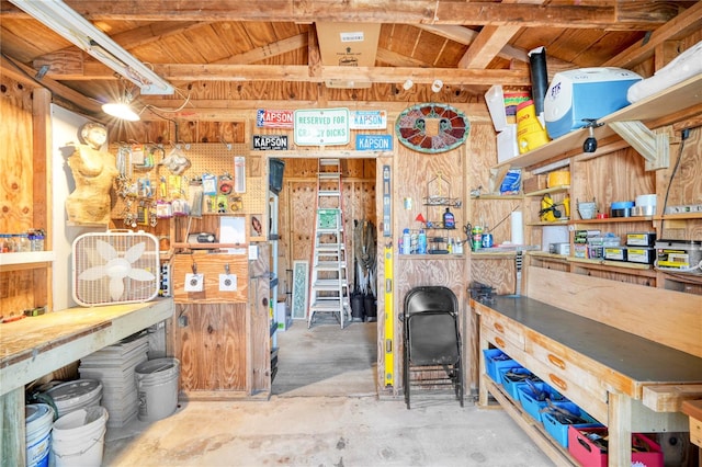 miscellaneous room featuring concrete flooring, a workshop area, and lofted ceiling