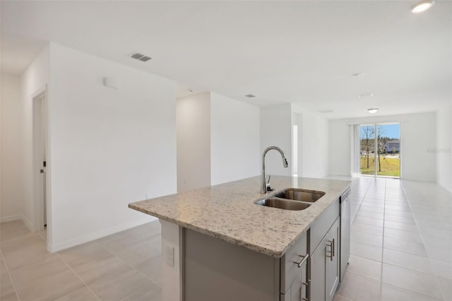 kitchen featuring light stone counters, stainless steel dishwasher, sink, a center island with sink, and light tile patterned flooring