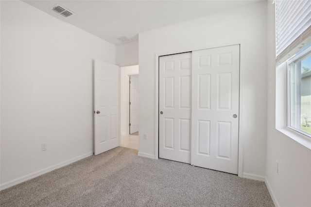 unfurnished bedroom with light colored carpet and a closet