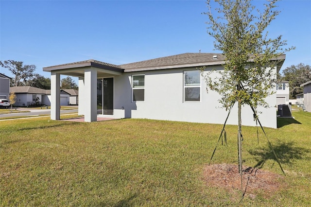 back of property with a yard and central AC unit